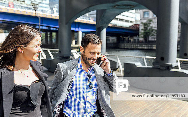 Smiling businessman on the phone and businesswoman in the city