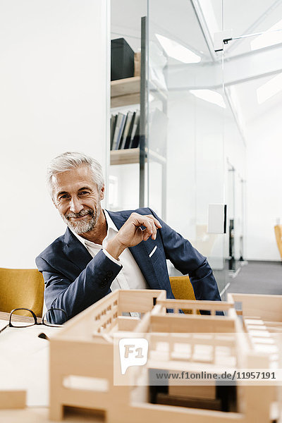 Portrait of smiling mature businessman with architectural model in office
