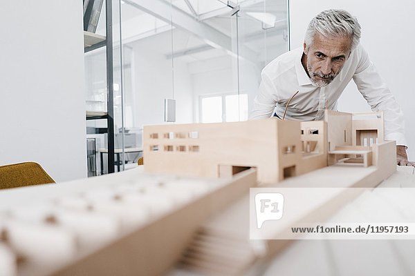 Mature businessman examining architectural model in office