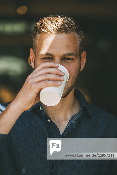 Portrait eines jungen Mannes mit Kaffee zum Mitnehmen