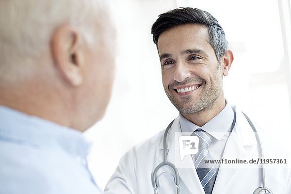 MODEL RELEASED. Male doctor smiling at senior patient.