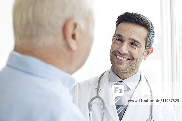 MODELL FREIGEGEBEN. Männlicher Arzt  der einen älteren Patienten anlächelt.