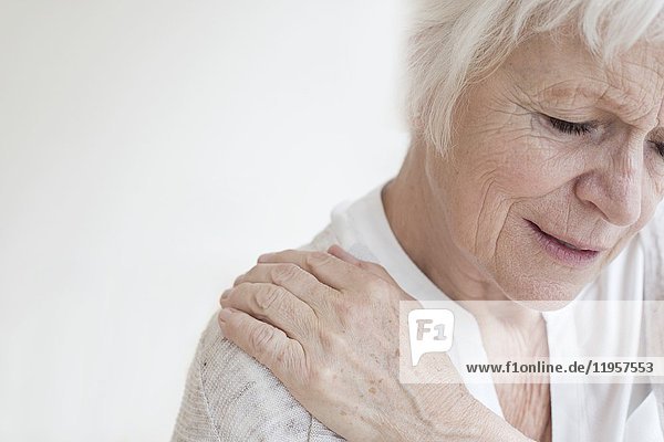 MODELL FREIGELASSEN. Eine ältere Frau reibt sich die schmerzende Schulter.