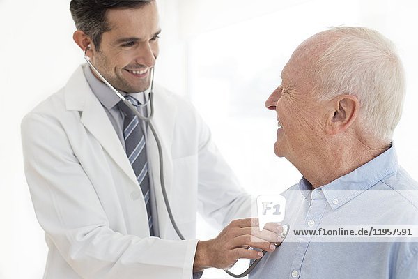 MODEL RELEASED. Male doctor examining senior patient  portrait.