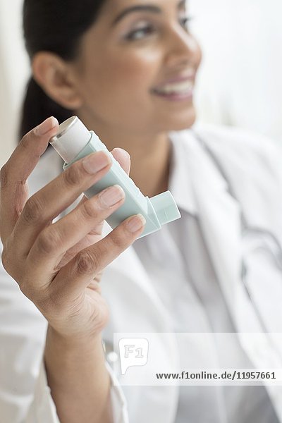 MODEL RELEASED. Female doctor holding inhaler.