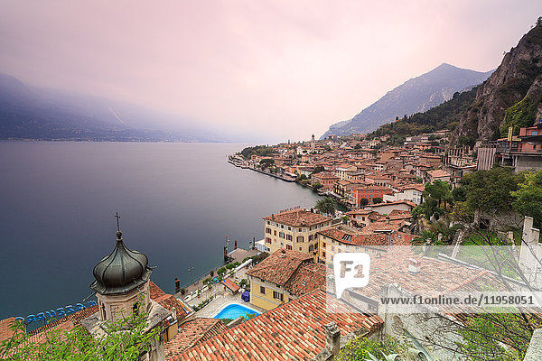 Pink sunrise lights up Lake Garda and the typical town of Limone Sul Garda  province of Brescia  Italian Lakes  Lombardy  Italy  Europe