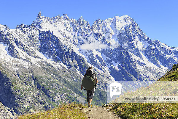 Wanderer läuft entlang des Weges mit Blick auf die Grandes Jorasses und den Riesenzahn  Venytal  Courmayeur  Aostatal  Italien  Europa