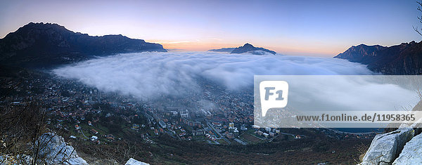 Panoramic of fog at sunrise above the city of Lecco seen from Monte San Martino Province of Lecco Lombardy Italy Europe