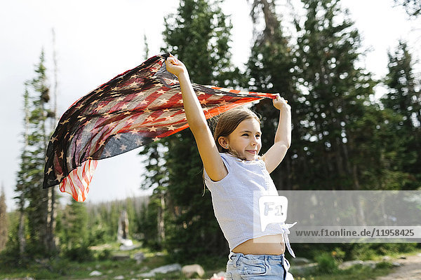 Mädchen (8-9) hält unsere Flagge im Wald