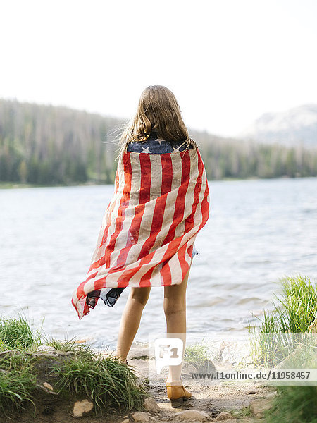 USA  Utah  Midway  Rückansicht eines Mädchens (8-9)  eingewickelt in eine US-Flagge  stehend am See