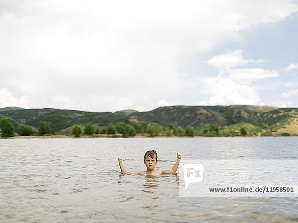 USA  Utah  Park City  Boy (6-7) flexing muscles in lake