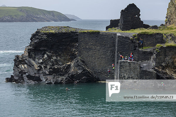 Coasteering-Aktivität mit Menschen  die vom ehemaligen Steinbruchgebäude an der blauen Lagune von Abereiddy springen  Pembrokeshire  Wales  Vereinigtes Königreich  Europa