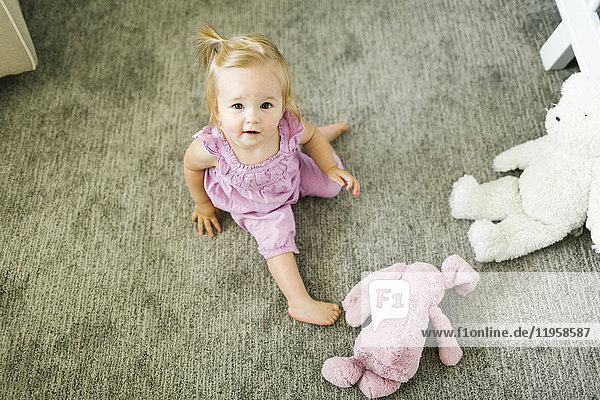 Porträt eines kleinen Mädchens (12-17 Monate) auf dem Boden sitzend