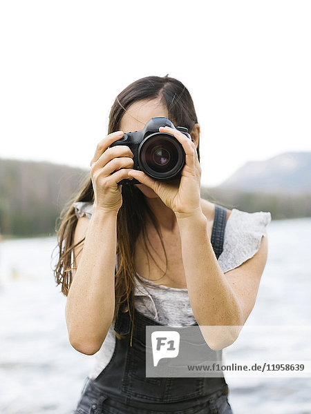 Woman taking pictures by lake