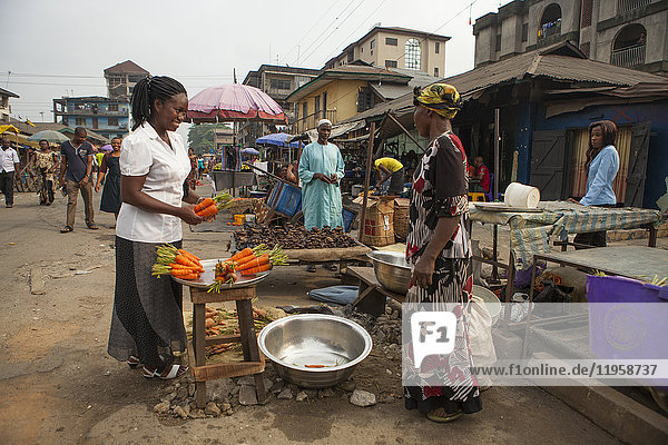 A woman buying carrots in the market in Nigeria  West Africa  Africa