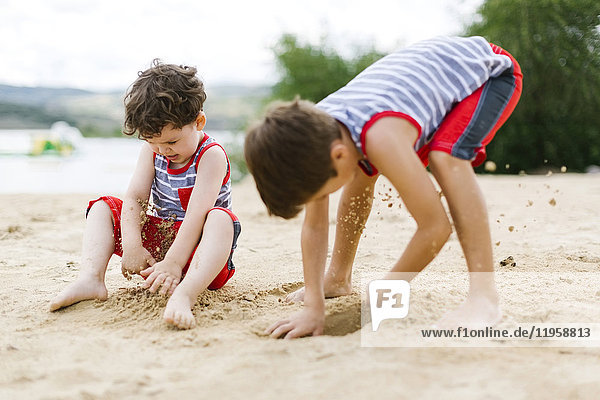 Brothers (4-5  6-7) playing on beach by lake