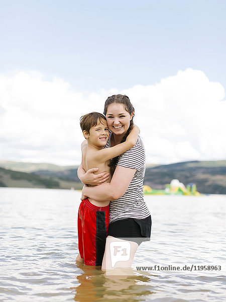 Mutter und Sohn (6-7) umarmen sich beim Waten im See