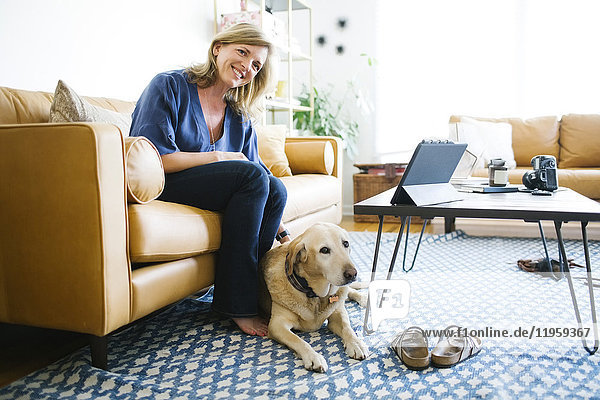 Woman stroking Labrador Retriever in living room