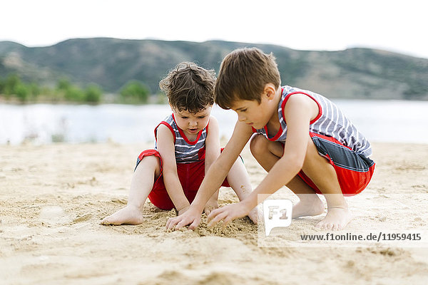 Brothers (4-5  6-7) playing on beach by lake