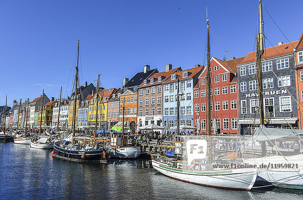 Nyhavn  das Hafenviertel aus dem 17. Jahrhundert mit einer Reihe farbenfroher historischer Gebäude  Promenade und festgemachten Segelschiffen in Kopenhagen  Dänemark.