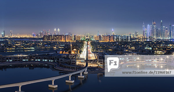 Stadtbild von Dubai  Vereinigte Arabische Emirate in der Dämmerung  mit beleuchteten Wolkenkratzern in der Ferne und einer Brücke über den Yachthafen im Vordergrund.