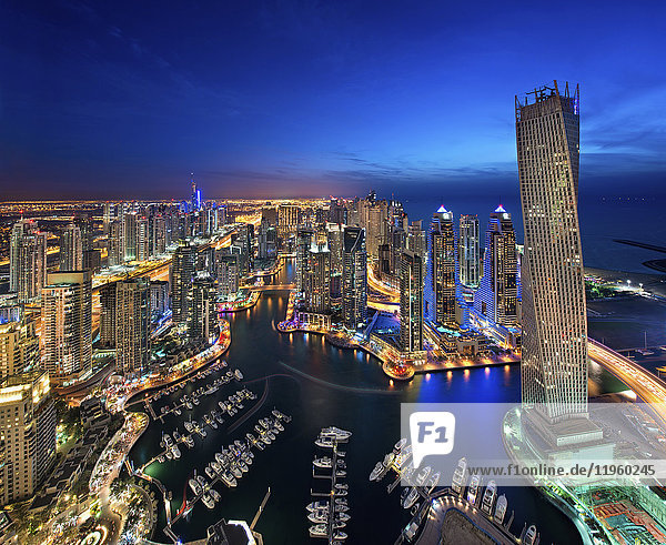 Luftaufnahme des Stadtbildes von Dubai  Vereinigte Arabische Emirate in der Abenddämmerung  mit beleuchteten Wolkenkratzern und dem Yachthafen im Vordergrund.