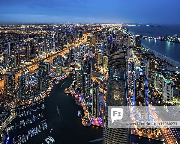 Luftaufnahme des Stadtbildes von Dubai  Vereinigte Arabische Emirate in der Abenddämmerung  mit beleuchteten Wolkenkratzern und dem Yachthafen im Vordergrund.