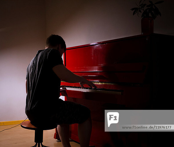Man playing piano in dimly lit room