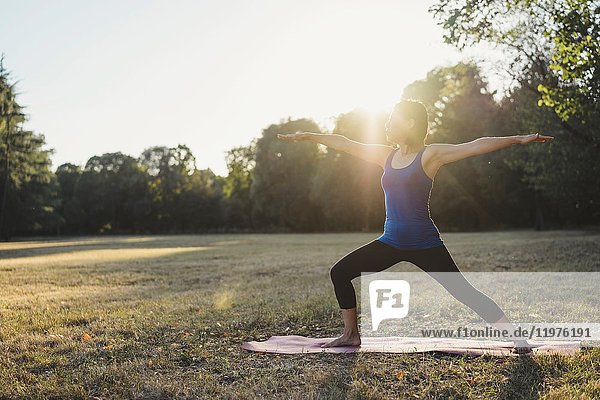 Mature woman in park  standing in yoga position  arms outstretched