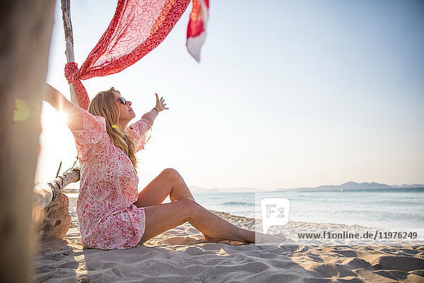 Frau sitzt mit offenen Armen am Strand  Palma de Mallorca  Islas Baleares  Spanien  Europa