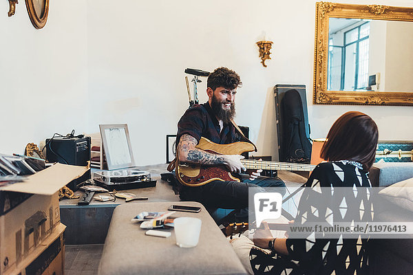 Couple playing electric guitars in apartment
