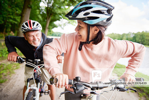 Mature couple cycling beside lake  laughing