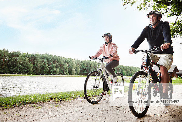 Mature couple cycling beside lake