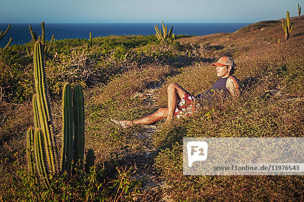 Man relaxing in grass  surrounded by cacti  Jericoacoara National Park  Ceara  Brazil