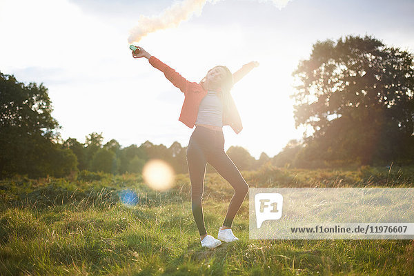 Junge Frau lässt Rauchschwaden im sonnenbeschienenen Feld ab