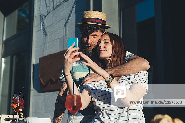 Ehepaar beim Selbstbedienungs-Smartphone im Straßencafé
