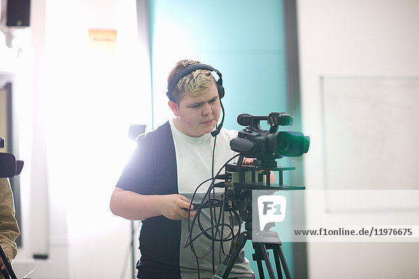 Young male college student filming in TV studio