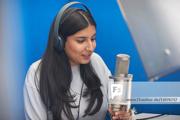 Young female college student at microphone in TV recording studio