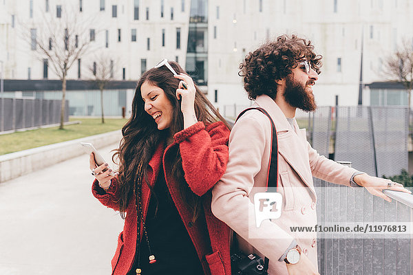 Junges Paar im Freien  junge Frau schaut auf Smartphone  lacht