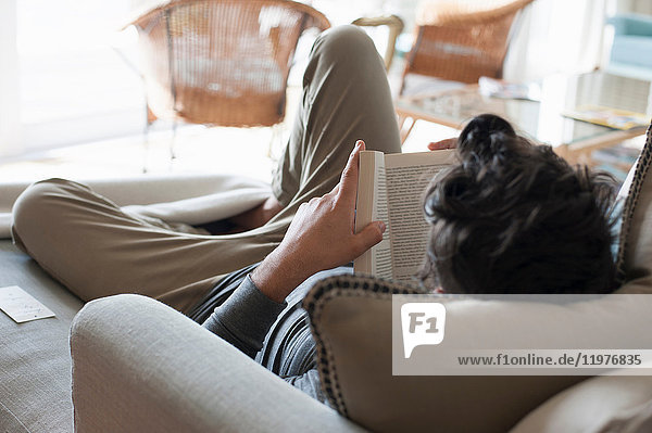 Mittelgroßer Mann entspannt auf Sofa  Buch lesen  Rückansicht