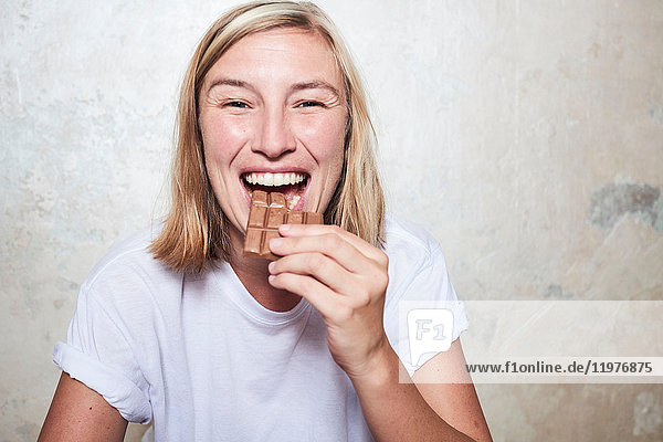 Porträt einer Frau  die eine Tafel Schokolade isst