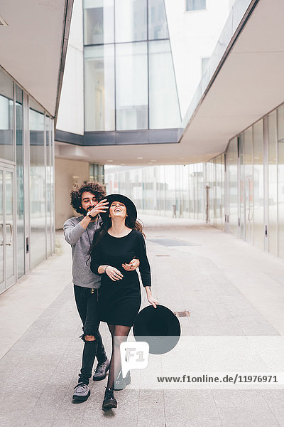 Junges Paar geht in städtischer Umgebung spazieren,  albert herum,  lacht