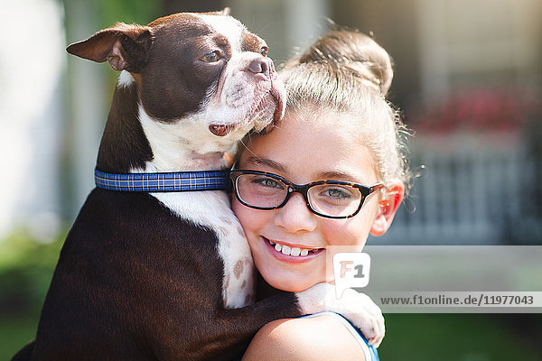 Porträt eines Mädchens mit Hund,  das lächelnd in die Kamera schaut