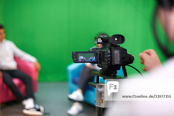 Junge männliche und weibliche Studenten üben im Fernsehstudio mit Green Screen