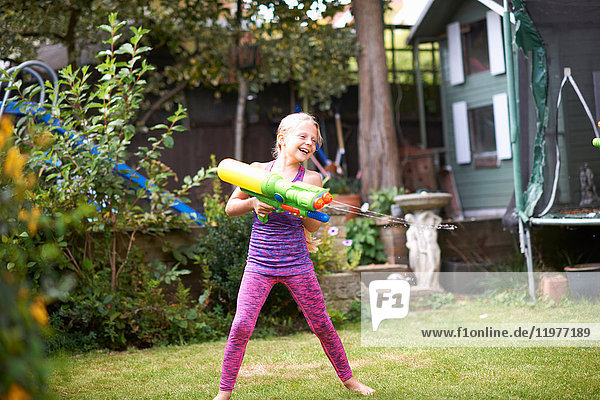 Girl squirting water gun in garden