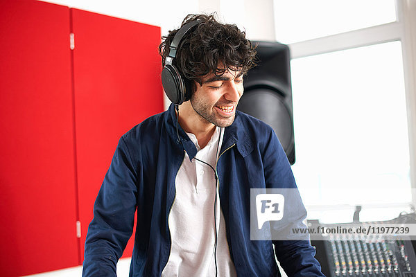 Junger männlicher College-DJ-Student hört Musik über Kopfhörer