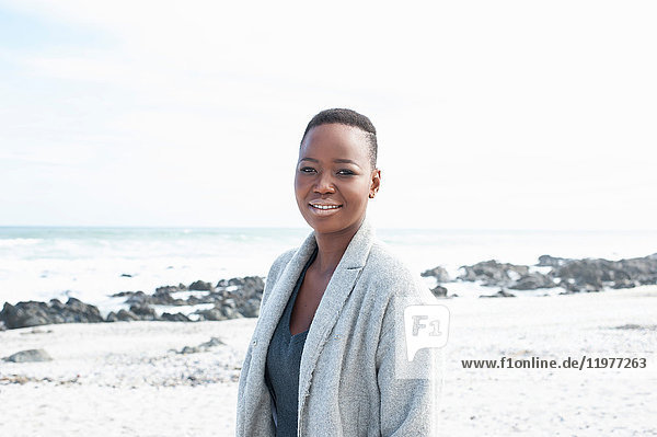Porträt einer jungen Frau  die am Strand steht und lächelt