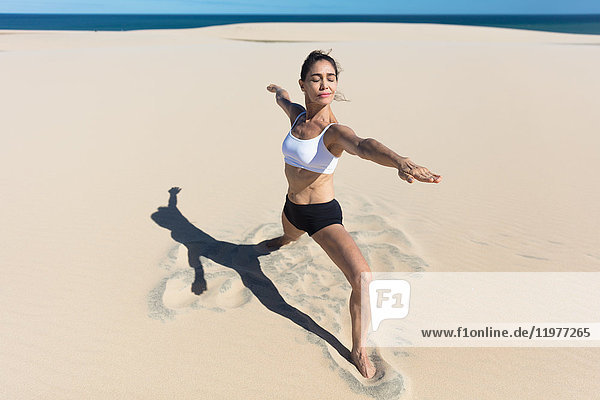 Frau am Strand Arme geöffnet und streckt sich in Yogastellung