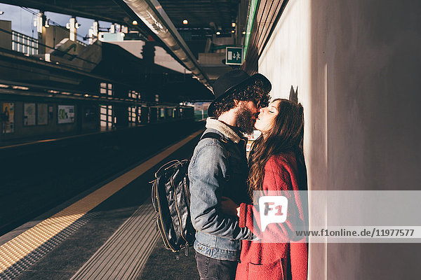 Junges Paar steht auf dem Bahnsteig und küsst sich