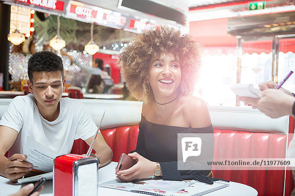 Young couple sitting in diner giving order to waitress